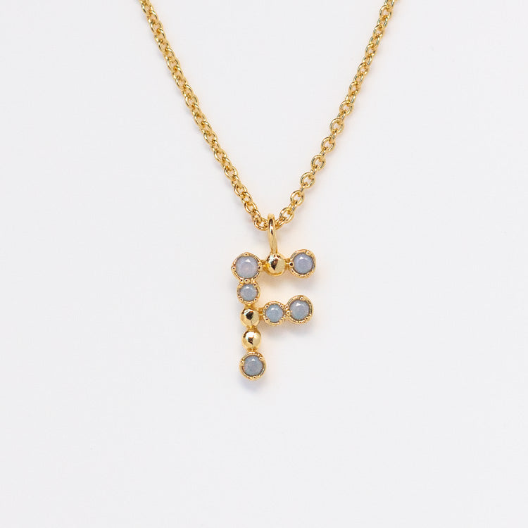 The Initial Charm Necklace Sample is a 14k yellow gold plated brass necklace featuring an F-shaped pendant with opalescent nano gems, shown against a white background.