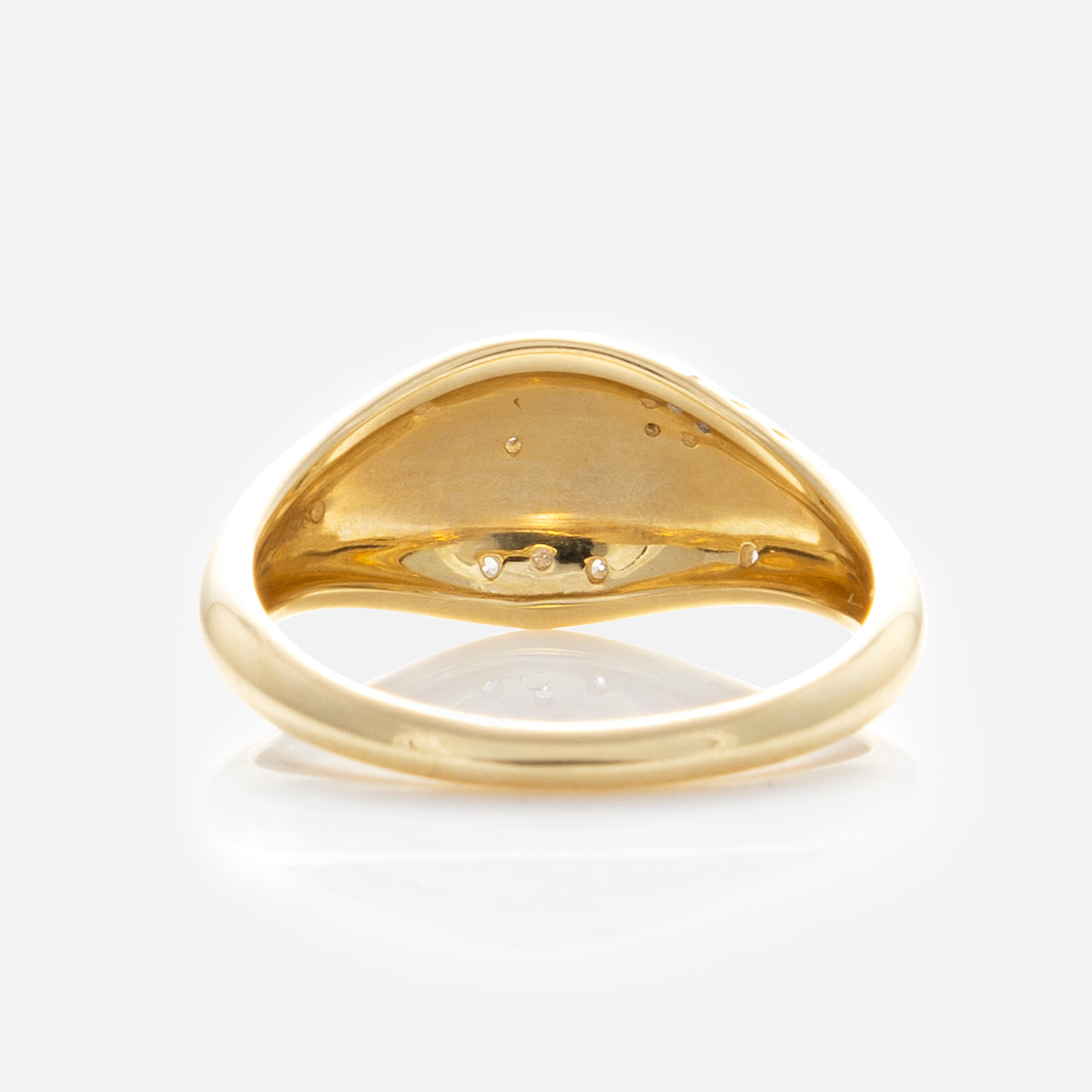 The Solid Gold Floral Etched Diamond Pinky Ring is shown from beneath, highlighting its smooth, polished interior with delicate indentations and a lustrous finish set against a plain white backdrop.