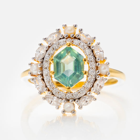 The Fern Green Topaz Statement Ring with Pearl Halo showcases an emerald-cut green topaz, surrounded by pearls and diamonds in an ornate oval setting, crafted in 14k gold vermeil on a white background.