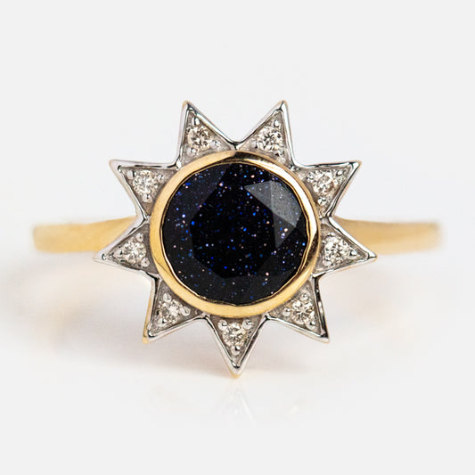 The Solid Gold Starburst Ring for Inspiration is a 9k gold ring with pointed tips, tiny clear stones on each point, and a sparkling large round dark blue center gemstone—perfect for elevating your style.