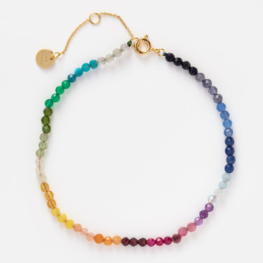 The Live by the Sun Rainbow Crystal Beaded Anklet features faceted round beads in a gradient rainbow from red to purple, finished with a gold chain and clasp—ideal for fans of natural crystal jewelry.