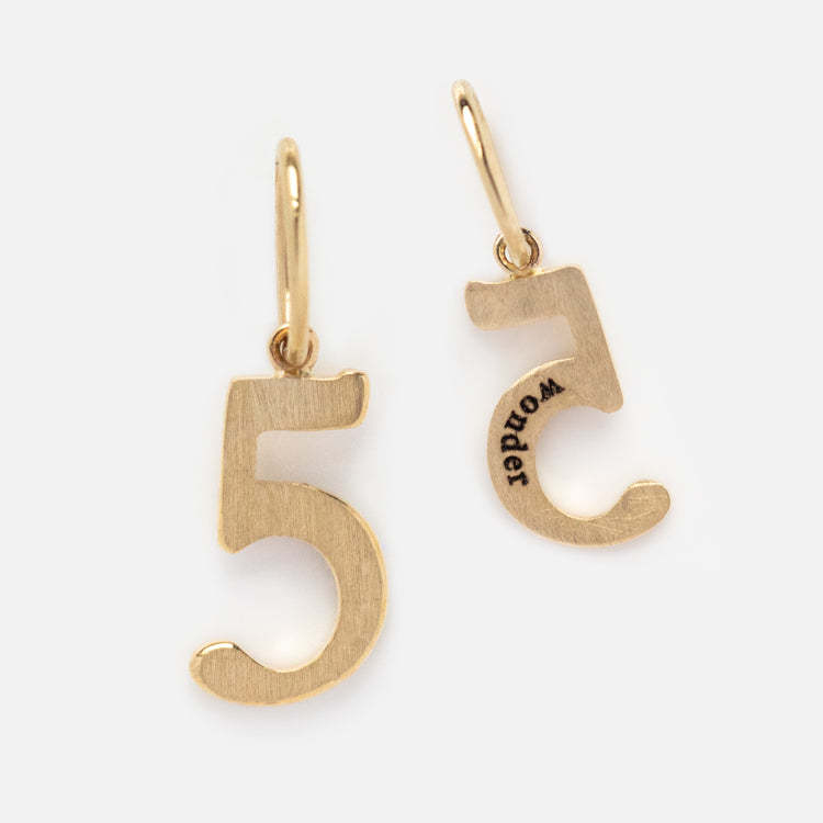 The Solid Gold Number Charm earrings feature a gold number 5—one facing forward, the other engraved with WORLD in black—on simple gold hoops. A unique gift for personalized jewelry lovers.