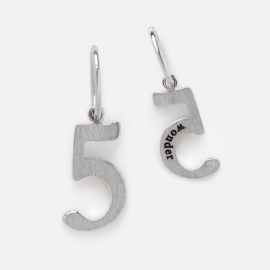 The Solid Gold Number Charm in White Gold is a pair of earrings shaped like the number 5. One earring features “WORLD” engraved backward, and both have hooks for easy wear.
