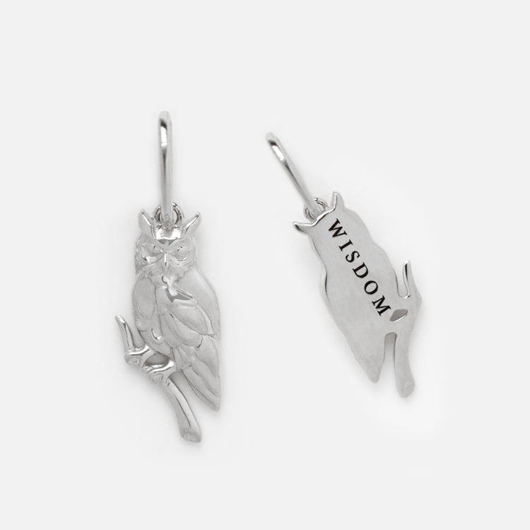 Two silver owl-shaped charms are displayed: one with detailed owl features on a branch, the other engraved WISDOM on its back. Both have loops for attaching, ideal for pairing with the Solid Gold Nature Charm in White Gold or adding pearl accents.