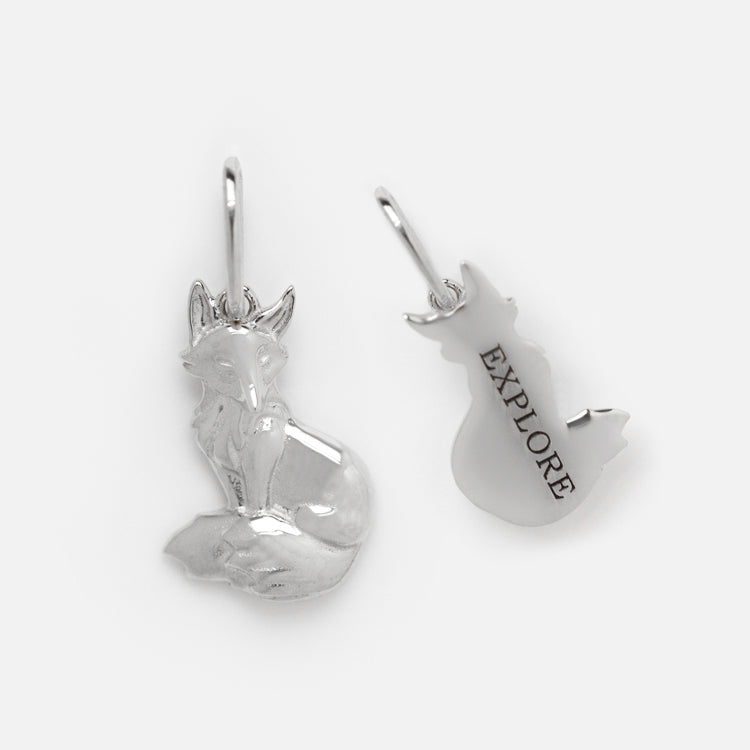 This Solid Gold Nature Charm in White Gold includes two fox-shaped pieces: one shows a sitting fox, the other its back with EXPLORE engraved. Both have loops for easy attachment—perfect for nature lovers jewelry.