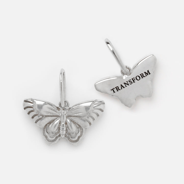 Two silver butterfly charms—one with a detailed design, the other engraved with TRANSFORM—perfect to pair with the Solid Gold Nature Charm in White Gold.