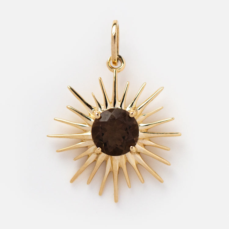 Solid Gold Amulet Charm featuring a round dark brown gemstone at the center of a sunburst design with pointed rays and a top loop for attaching to a necklace—a local eclectic exclusive.