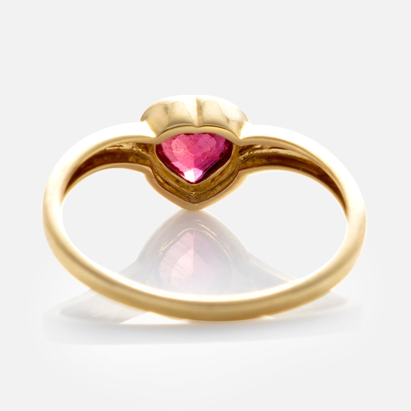 The Solid Gold Bezel Set Ruby Heart Ring showcases a heart-shaped ruby at its center, viewed from the side on a white background. Its smooth, polished solid gold band offers timeless elegance—a classic piece from Family Gold.