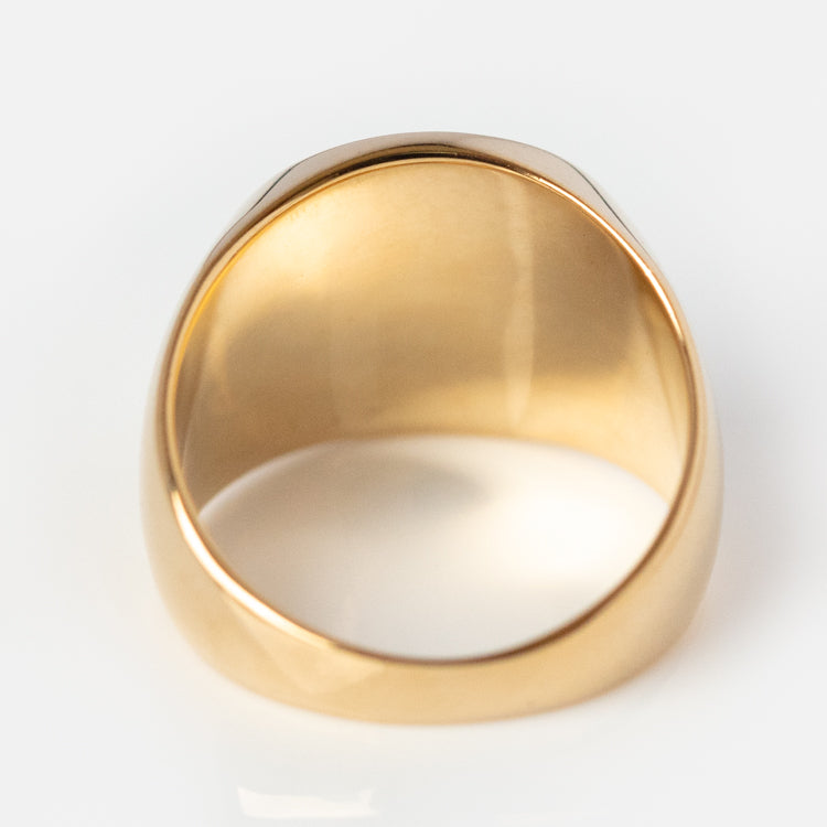 A close-up of the Everything Will Be Ok Pinky Signet Ring, 14K gold plated, viewed from below to show its smooth, polished interior and wide band against a white background.
