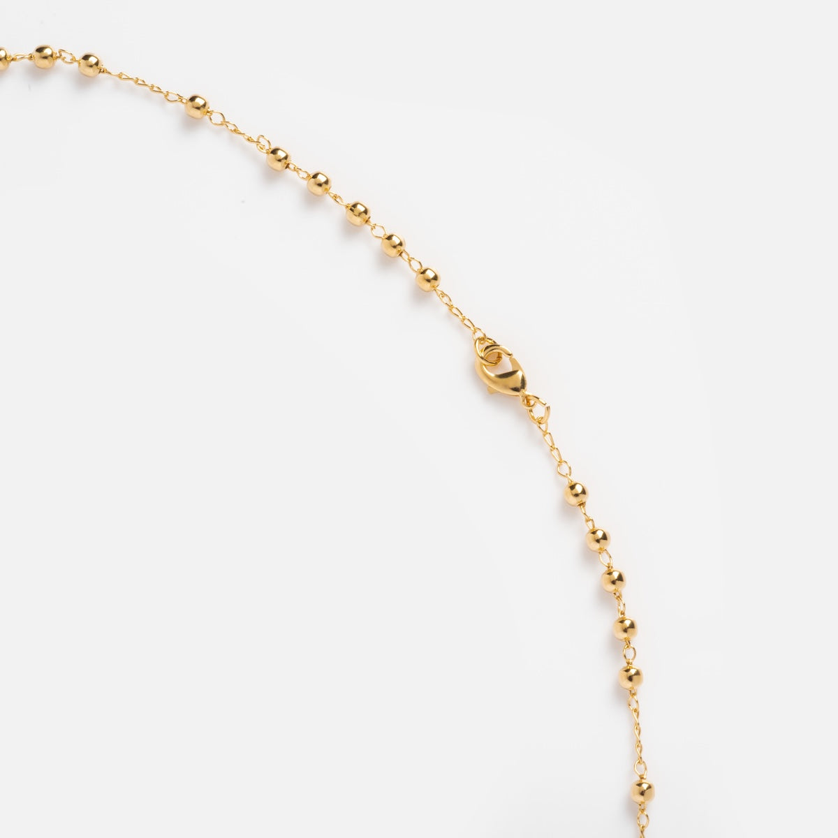 The Gold Rosary Necklace features a delicate 14k gold plated chain with evenly spaced small round beads and a lobster clasp, showcased on a plain white background—a timeless piece of faith jewelry.