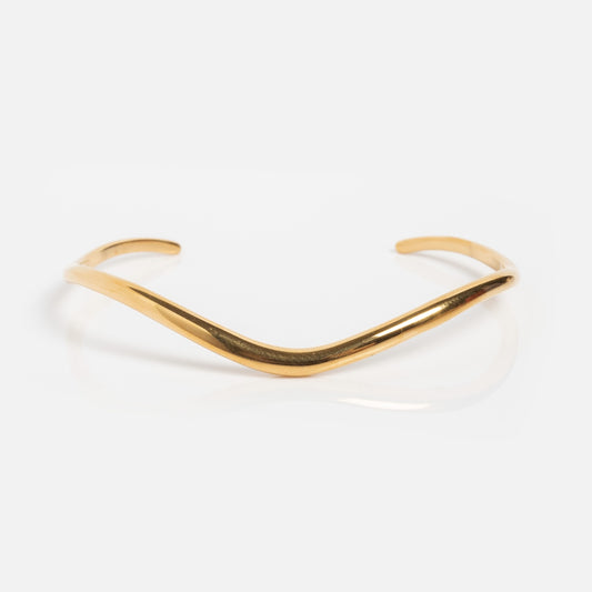 The Swell Cuff Bracelet features a minimalist design with an 18k yellow gold plated finish, gentle V-shaped curve, and open cuff style, shown on a plain white background.