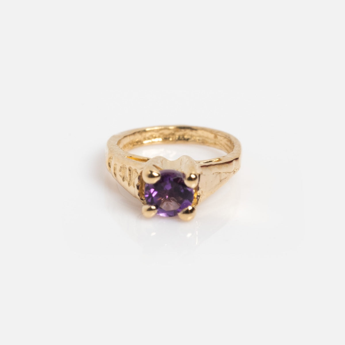 The 14k Littlest Birthstone Ring Charm by Charlie and Marcelle features a textured gold band and a round purple gemstone in a four-prong setting, displayed on a plain white background.