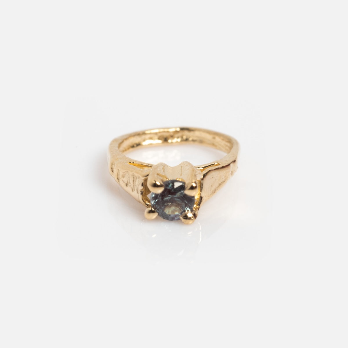The 14k Littlest Birthstone Ring Charm by Charlie and Marcelle features an engraved gold band and a round dark gemstone in a four-prong setting, shown on a white background—ideal as a birthstone ring charm.