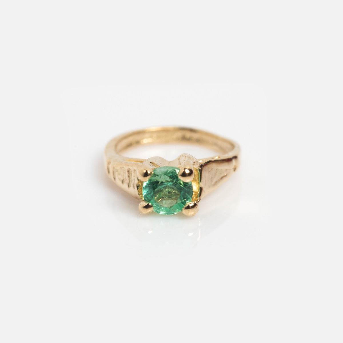The 14k Littlest Birthstone Ring Charm by Charlie and Marcelle features a round green gemstone in a prong setting, shown on a plain white background.