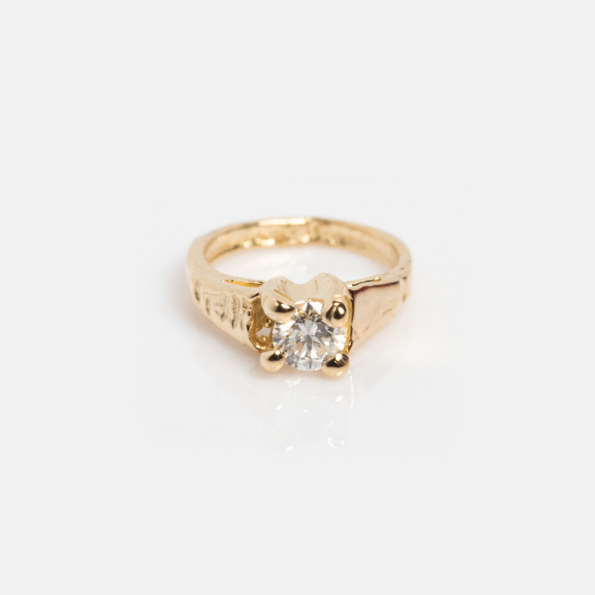 A gold ring by Charlie and Marcelle with a single round diamond in a raised four-prong setting, shown on a plain white background. Pairs beautifully with their 14k Littlest Birthstone Ring Charm or solid gold necklace charm.