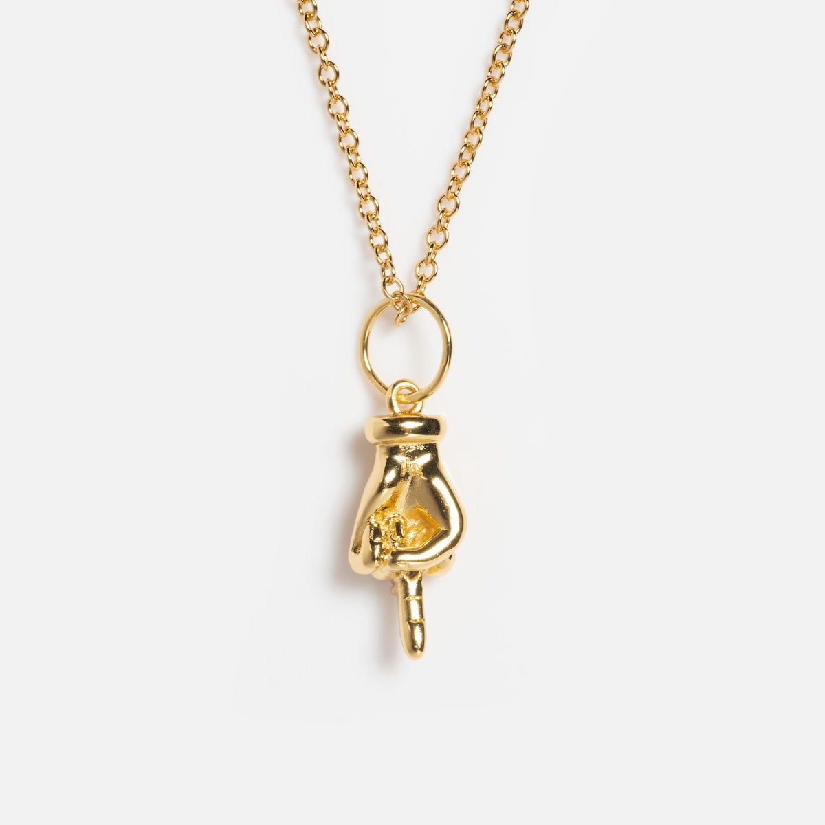 The Kiss Off Necklace showcases a hand-shaped pendant with a pointing gesture, plated in 14k gold, suspended from a dainty gold chain.