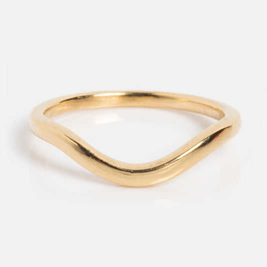 The 14k Low Tide Curved Band features a simple, thin gold design with a gentle wave, ideal for stacking. Shown on a plain white background.