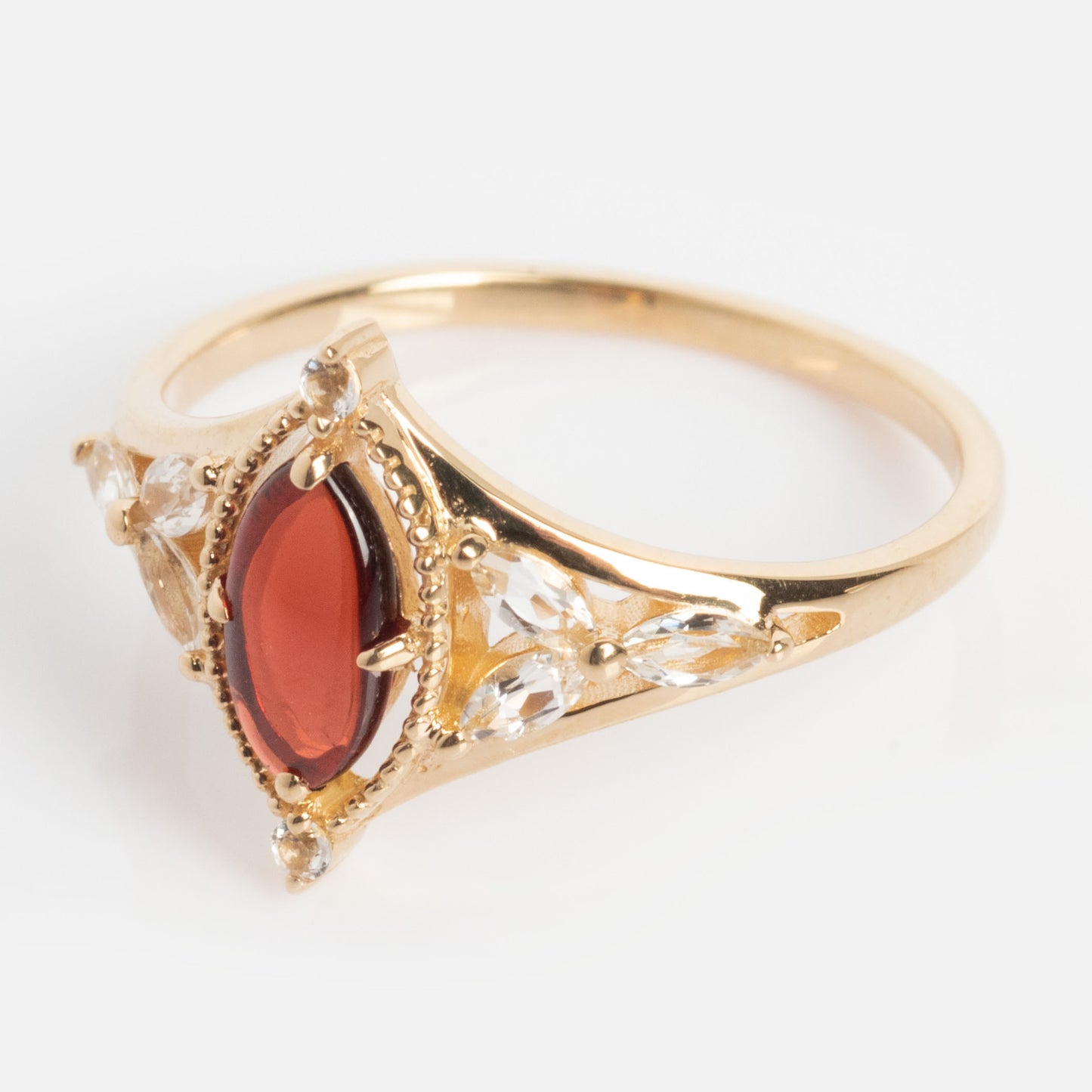 The Solid Gold 2026 January Capsule Art Deco Garnet Ring showcases a marquise-shaped January birthstone at its center, accented by clear stones in an ornate design flanking the main gem.