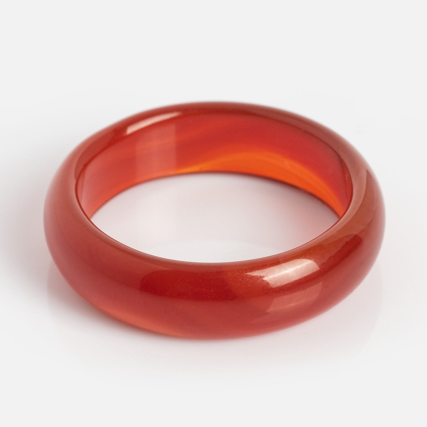 A smooth, glossy Persimmon Dark Orange Agate Stone Ring with a translucent red-orange hue, evoking natural agate, displayed against a white background.