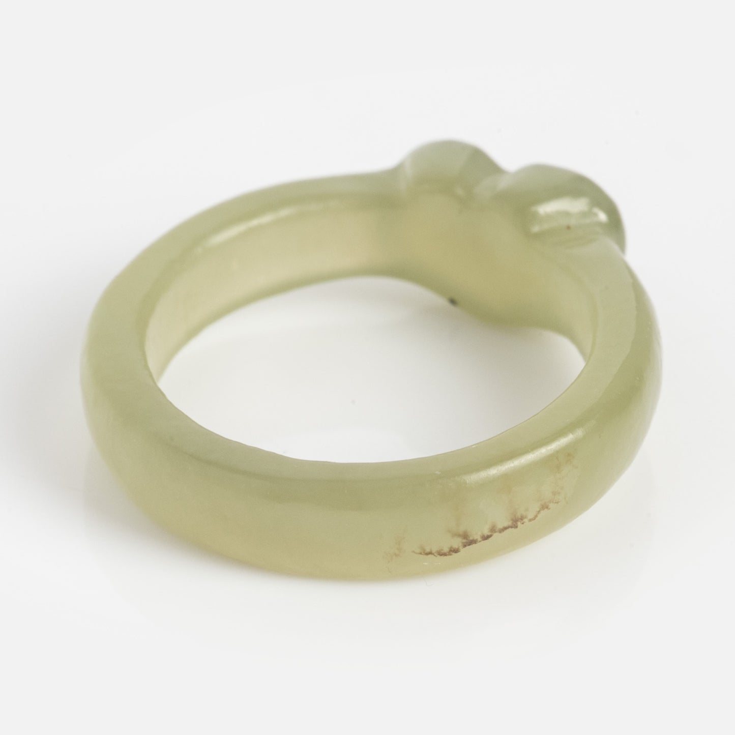 The Heart Jade Ring features light green jade with a smooth, 3.5 mm rounded band, a slightly uneven surface, a small raised area at the top, and a natural brownish mark on the side.