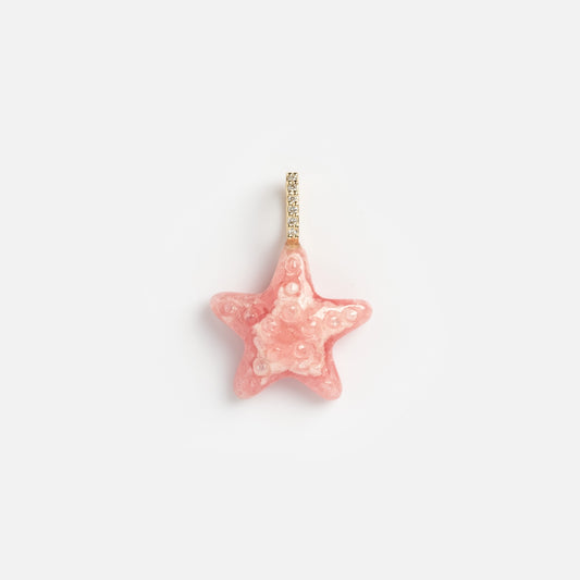 The 14k Pink Rhodochrosite and Diamond Sea Star Charm features a glossy, textured pink star shape with a sparkling diamond and 14k gold loop, displayed on a plain white background.