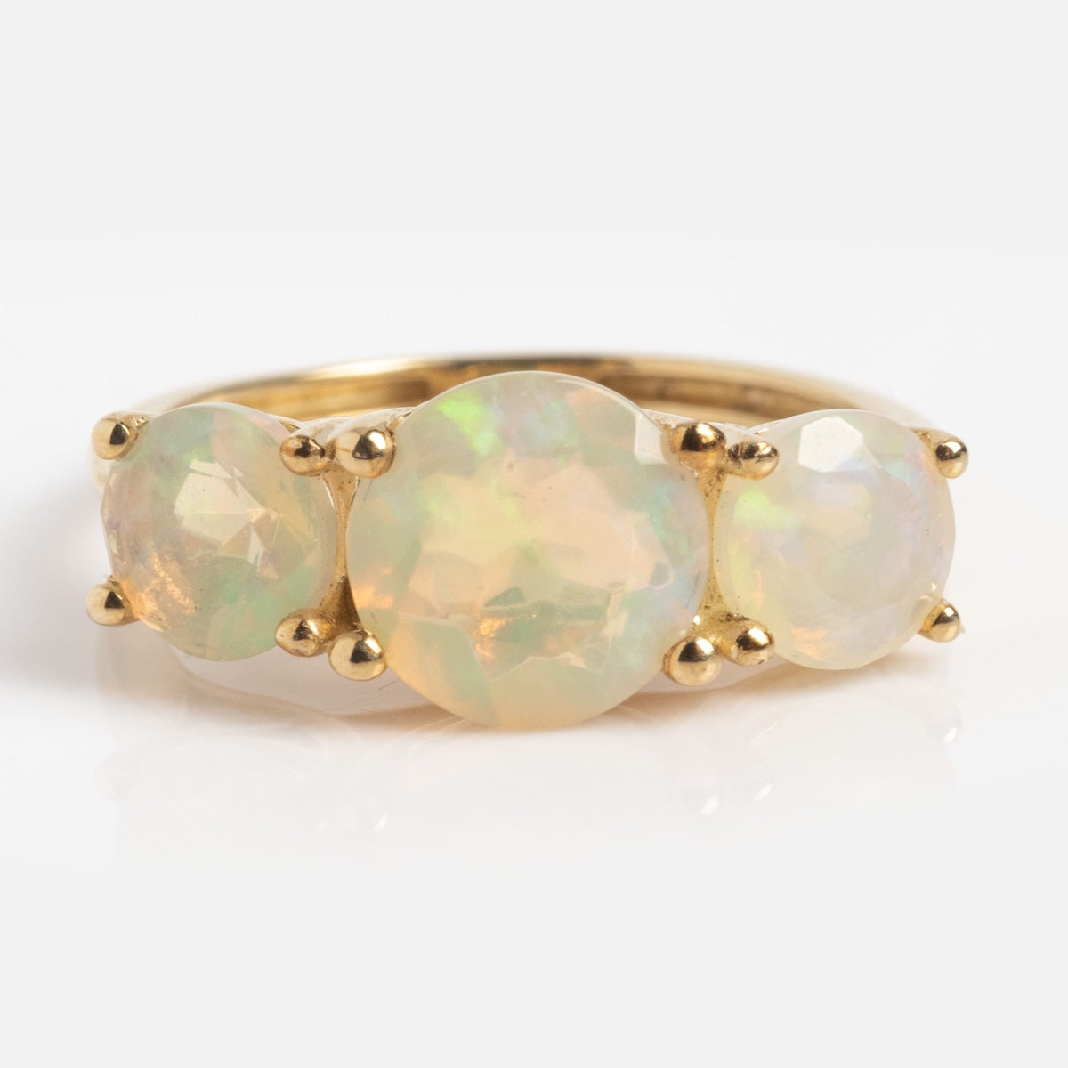The Solid Gold Trilogy Birthstone Pinky Ring in size 5 features three 7mm round faceted African opals set side by side in prongs, crafted from 9k solid yellow gold. Iridescent gemstones stand out against a plain white background.