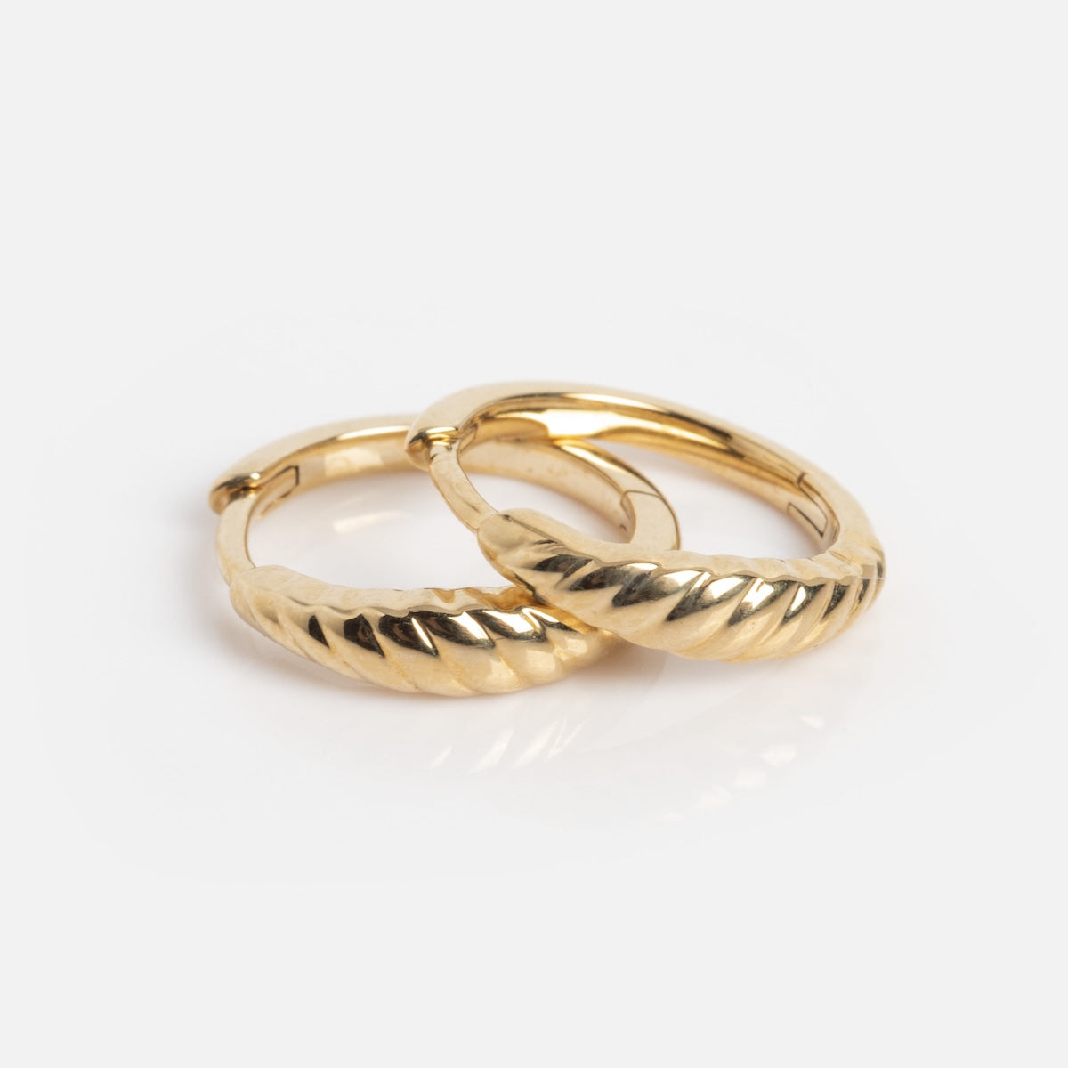 The Solid Gold Dainty Textured Huggie Hoops Sample features small 9k gold earrings with a twisted, ridged design, shown on a plain white background.