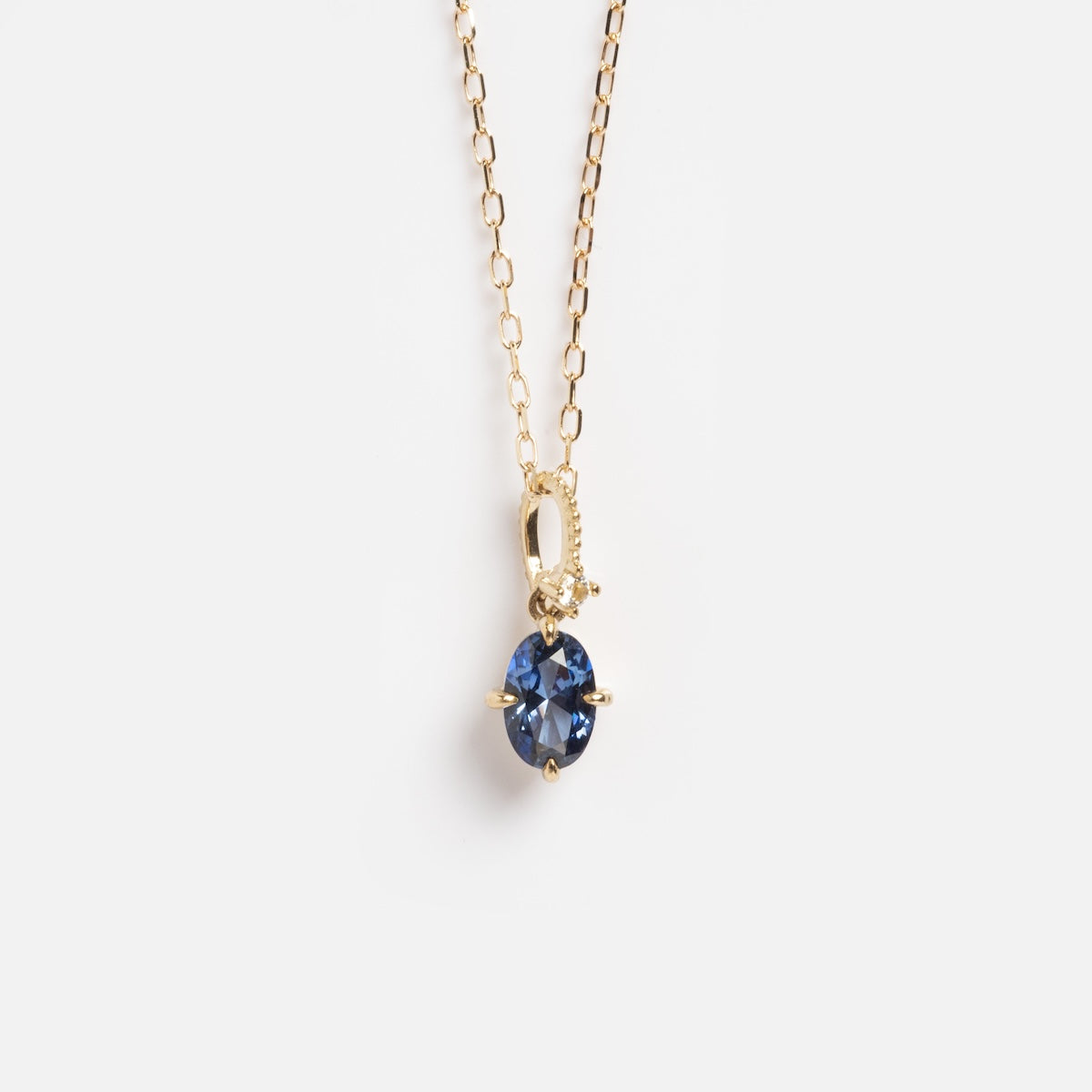 The Solid Gold Vintage Inspired Tanzanite Pendant Necklace Sample features an oval lab tanzanite in a four-prong 9k yellow gold setting, displayed on a plain white background.