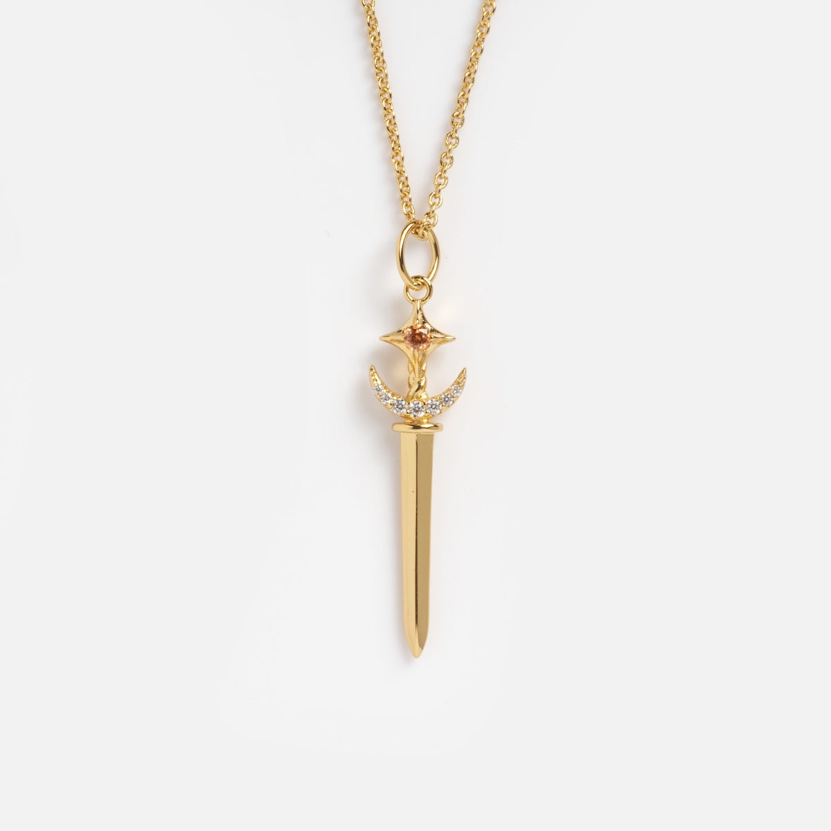 The Dagger Necklace Sample is a 14k gold plated necklace with a brass sword-shaped pendant, featuring a crescent moon and star at the top and accented with small white CZ gemstones above the blade.