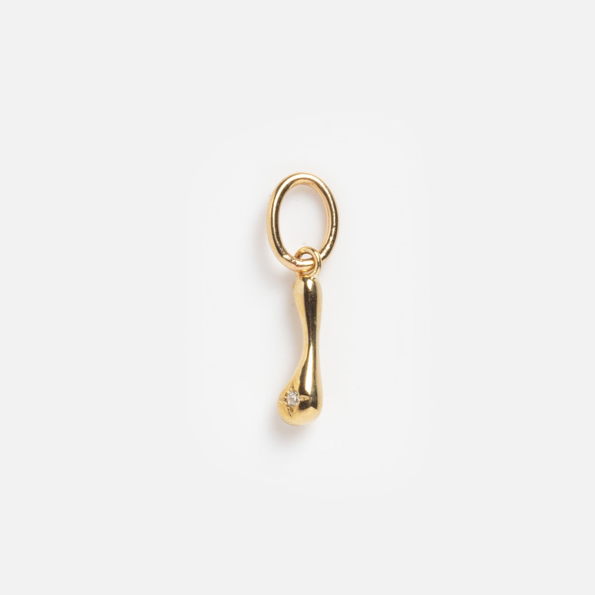 The Solid Gold Wavy Monogram Charm 'I' Sample is a small, gold pendant with an elongated, subtly curved drop shape and a circular loop, featuring a tiny gemstone near the rounded end, shown on a plain white background.