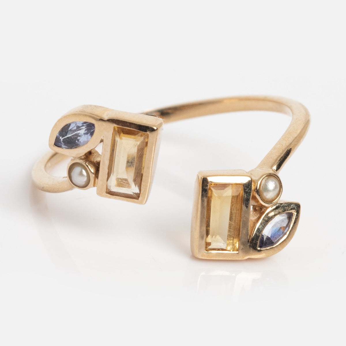 The Solid Gold Open Topaz Tanzanite and Pearl Twist Ring (Sample Size 7) features an open design with two rectangular yellow topaz stones, two small freshwater pearls, and two marquise-shaped tanzanites at each end.