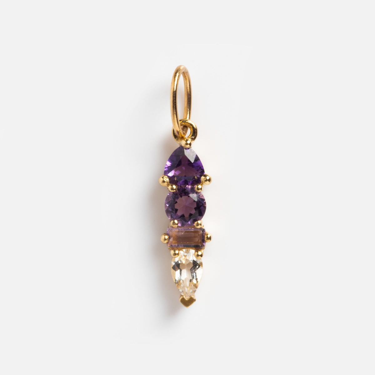 A solid gold pendant, the Solid Gold Modern Ombre Birthstone Charm showcases three vertically aligned gems—pear and round purple stones above a clear tapered rectangle—all set in gold prongs. A striking addition to any collection.