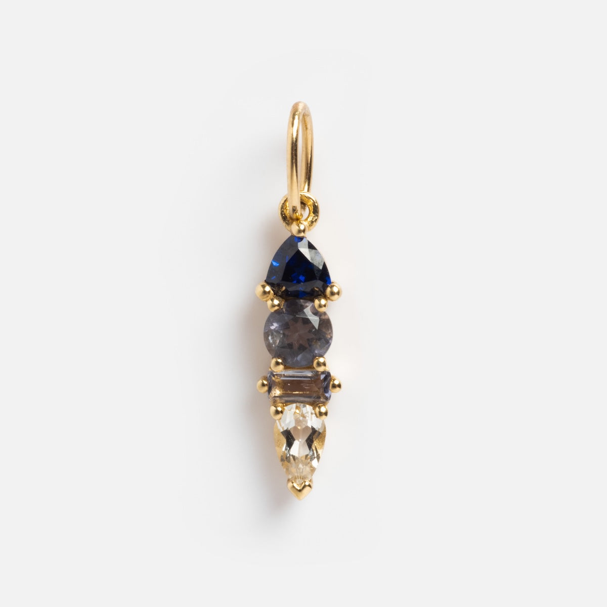 The Solid Gold Modern Ombre Birthstone Charm features three vertically aligned gemstones—blue, gray, and clear—in prong settings with a small gold loop for easy attachment to your necklace or bracelet.
