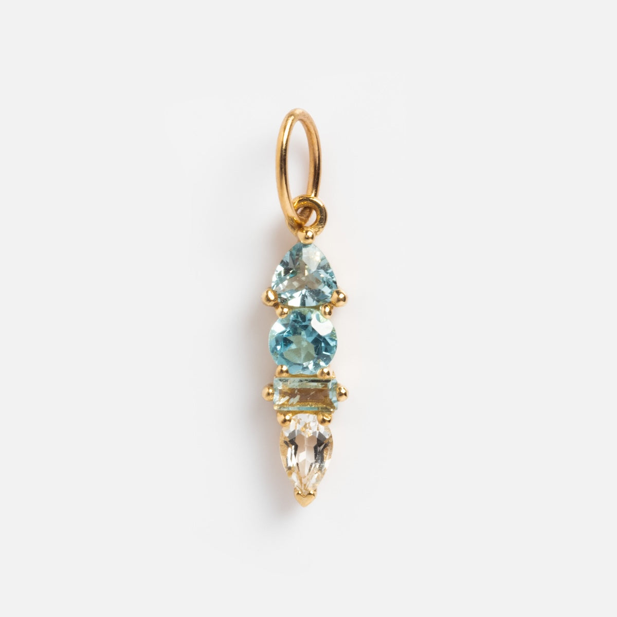 The Solid Gold Modern Ombre Birthstone Charm features three vertically aligned gemstones—a blue triangle at the top, a round blue center, and a clear teardrop below—with a gold ring for easy attachment.