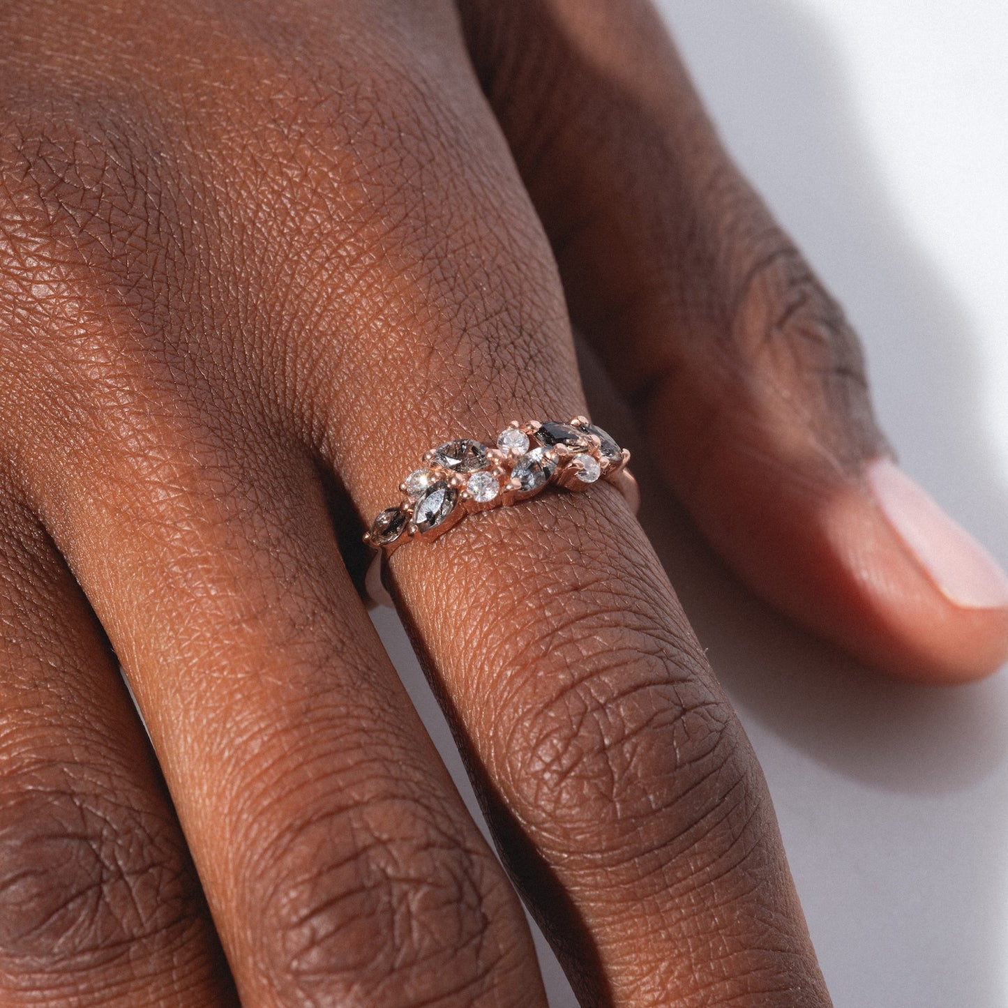 A close-up shows the Gemstone Orchard Ring—a gold band adorned with small, sparkling gemstones including London blue topaz, set in a floral-inspired design—worn on the ring finger.