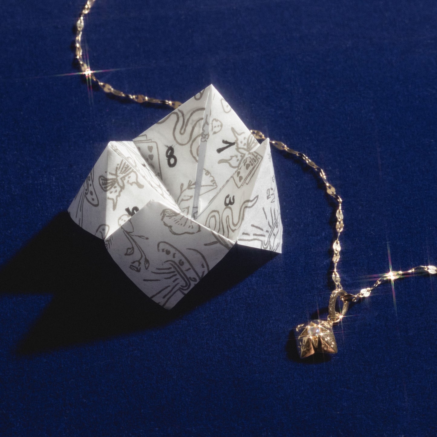 Origami fortune teller with a gold chain on a blue background