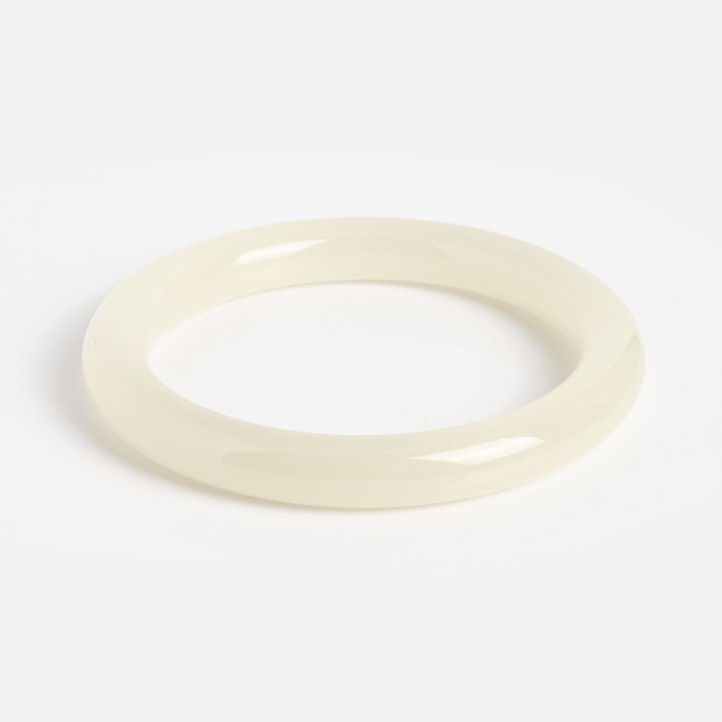 The 1994 Off White Thin Jade Bangle is a glossy, off-white round bangle with a smooth surface, expertly crafted from natural jade and shown on a plain white background.