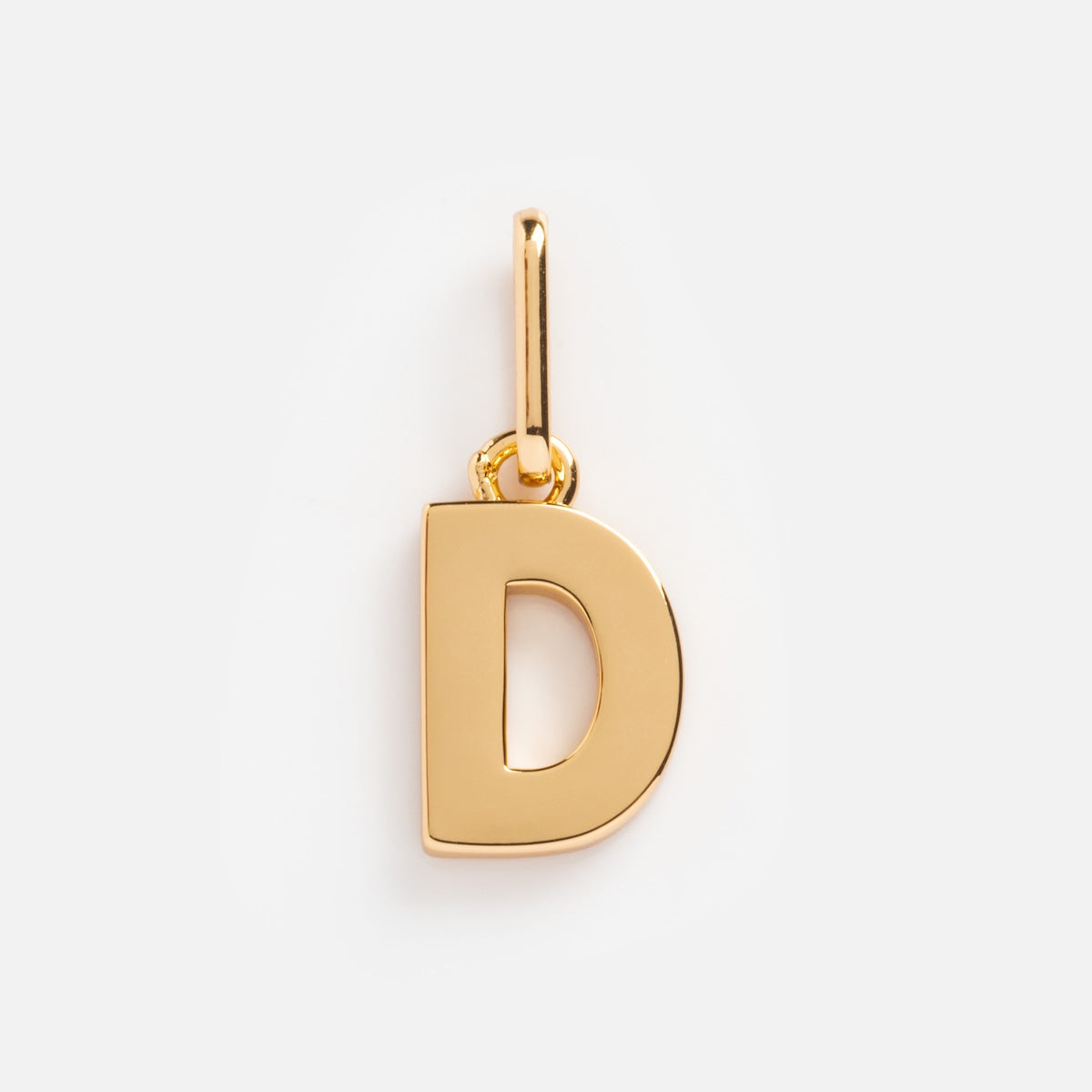 The Be You Initial Charm is a polished gold pendant in the shape of D, featuring a small loop for adding to your favorite necklace or bracelet. This personalized jewelry piece is shown against a plain white background.