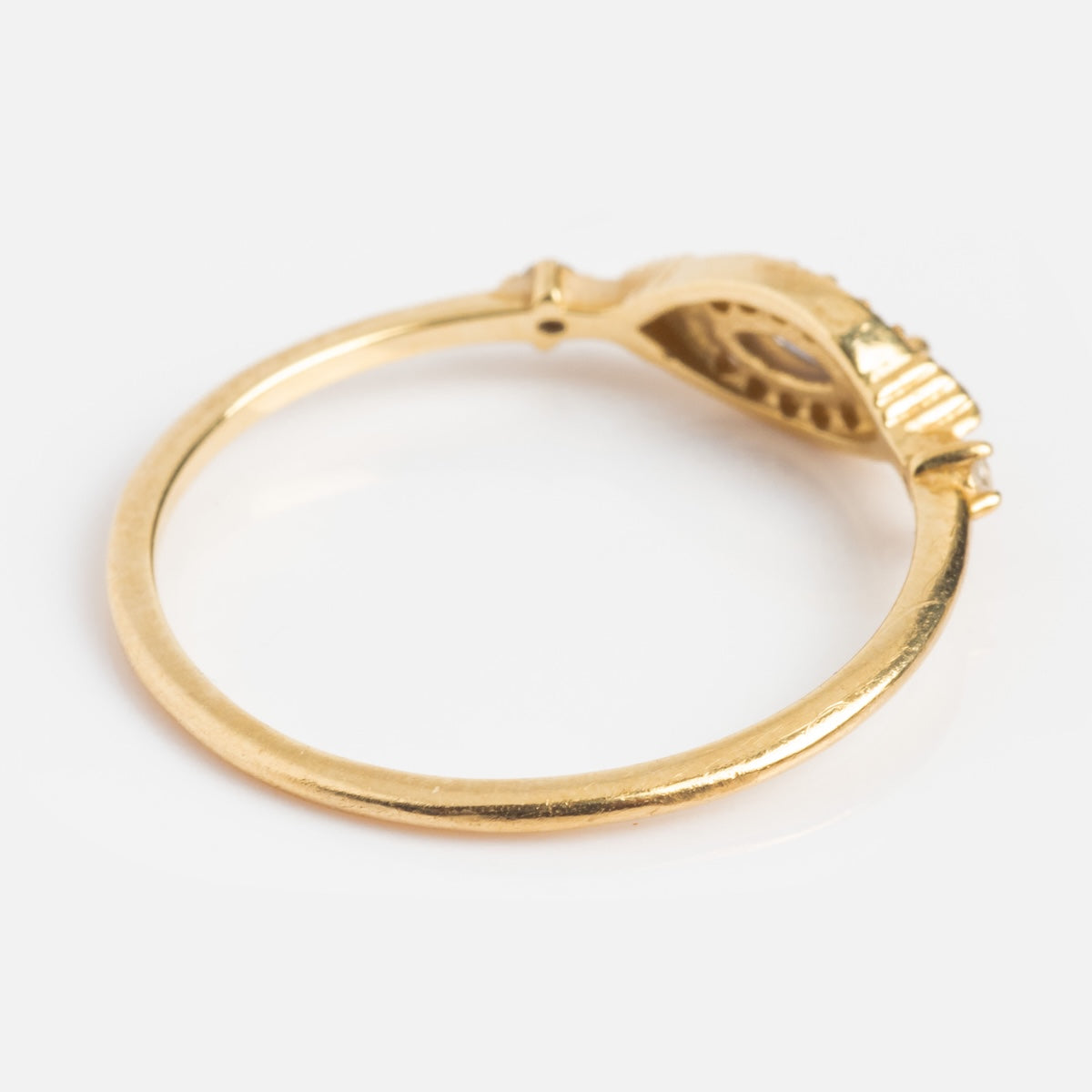 The Solid Gold Iolite Evil Eye Ring features a thin band and raised oval setting for a gemstone, shown from the side on a white background—ideal as an elegant statement piece.