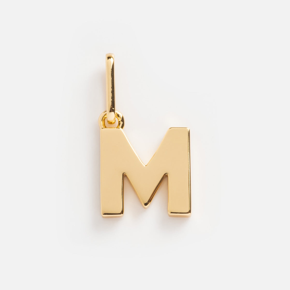Be You Initial Charm—gold pendant shaped like the letter M with a smooth, shiny finish and a small vertical loop at the top, perfect for adding a personalized touch to your jewelry collection. Shown on a plain white background.