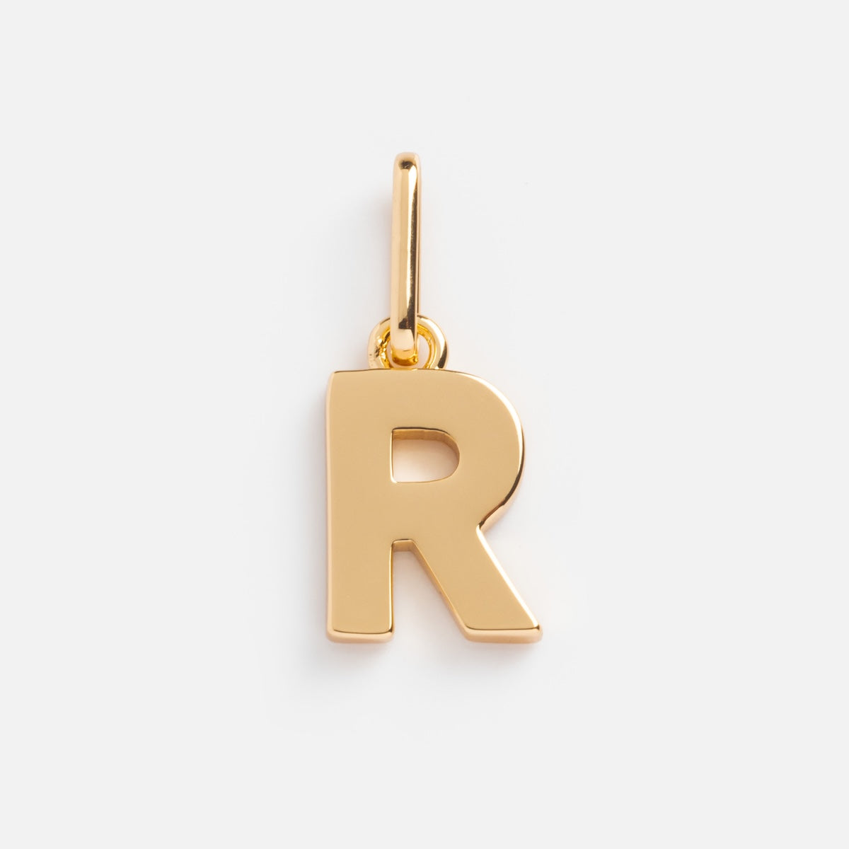 The Be You Initial Charm is a gold pendant shaped like the letter R, complete with a small loop for adding to a chain. This personalized piece stands out as the perfect accessory for initial jewelry lovers. Shown on a plain white background.