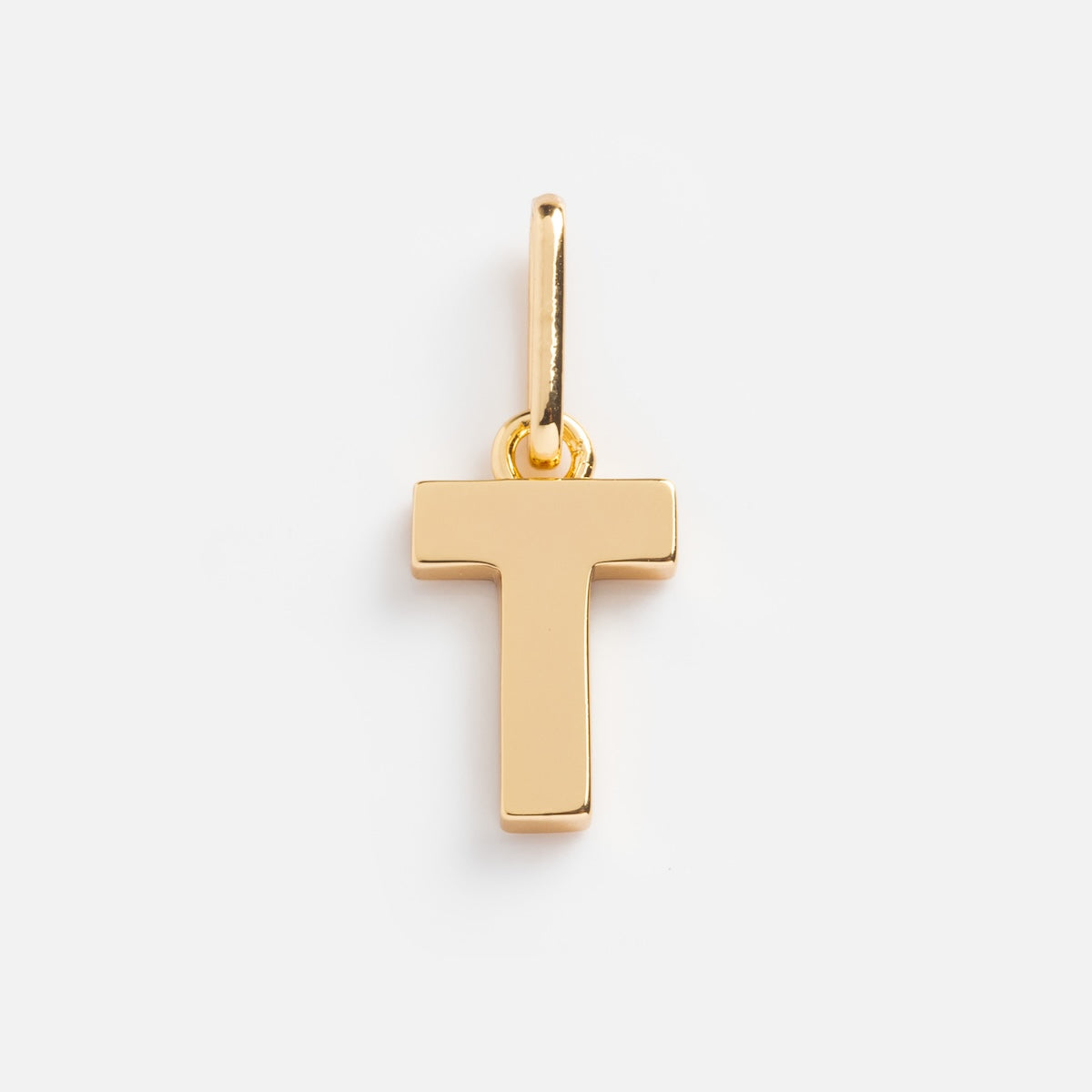 The Be You Initial Charm is a gold pendant shaped like the letter T, featuring a smooth, shiny finish and a top loop for attaching to a chain—ideal as personalized jewelry. Shown on a plain white background.