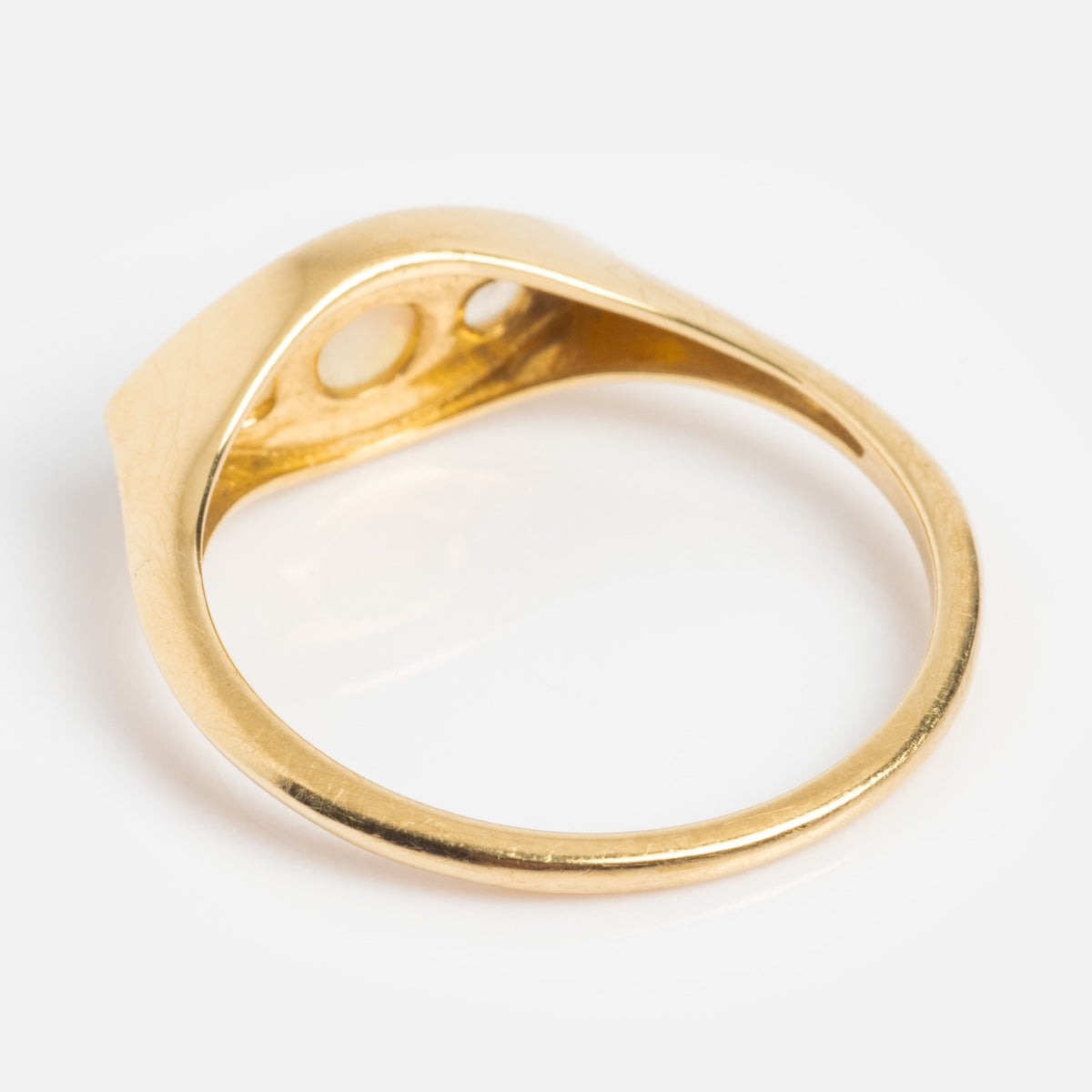 The Solid Gold Opal Evil Eye Signet Ring features a smooth, polished band and a flat, slightly raised top with open bezel details—an elegant piece inspired by timeless design.