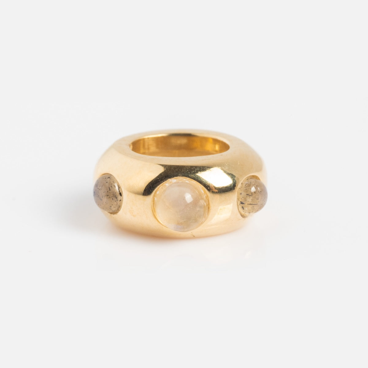 The Solid Gold Spacer Charm is a chunky gold ring with a smooth, rounded band and three round, translucent gemstones set evenly around it. The design is reminiscent of elegant yellow gold charms. Displayed on a plain white background.
