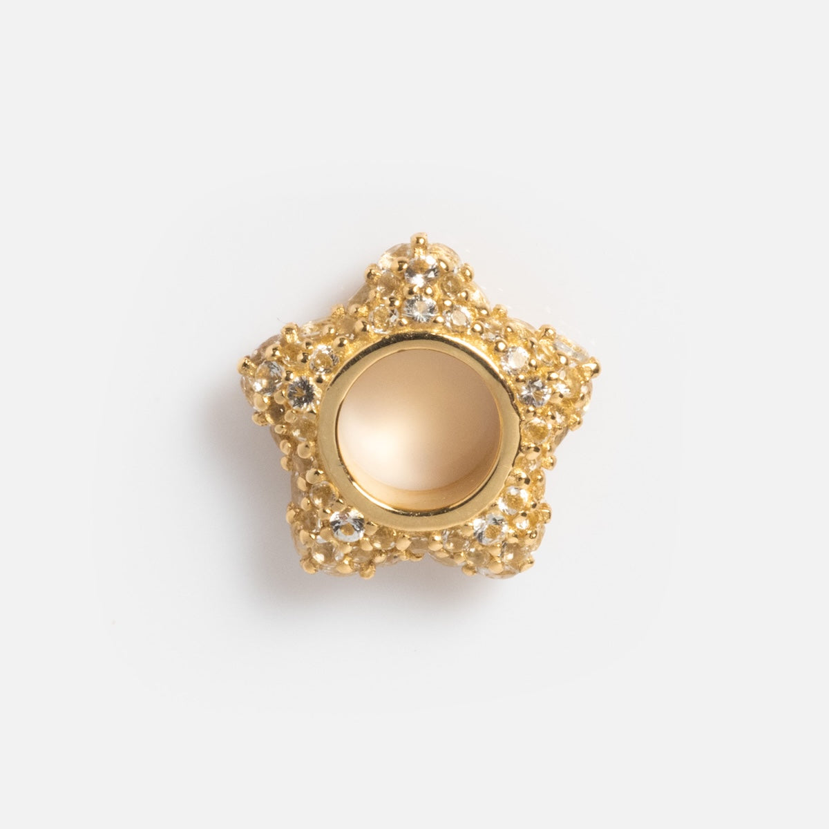 A solid gold spacer charm, star-shaped with a textured surface and clear crystals, is shown on a white background. This elegant piece features a hollow center and showcases the brilliance of yellow gold in refined jewelry designs.