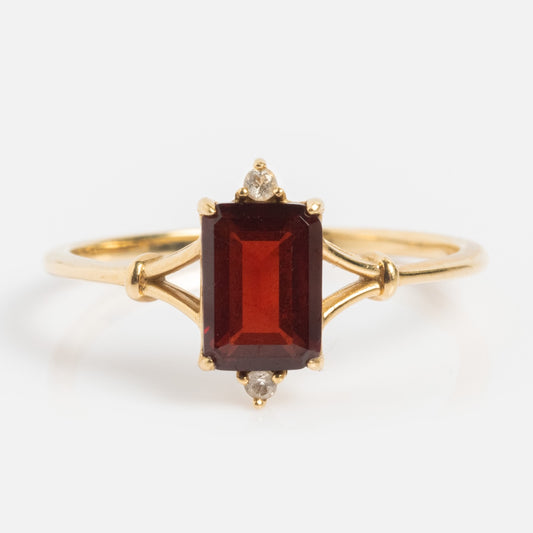 The Solid Gold 2025 January Capsule Garnet Statement Set features a rectangular deep red garnet—Januarys birthstone—flanked by two clear stones on a delicate gold band, and comes with a free gift.
