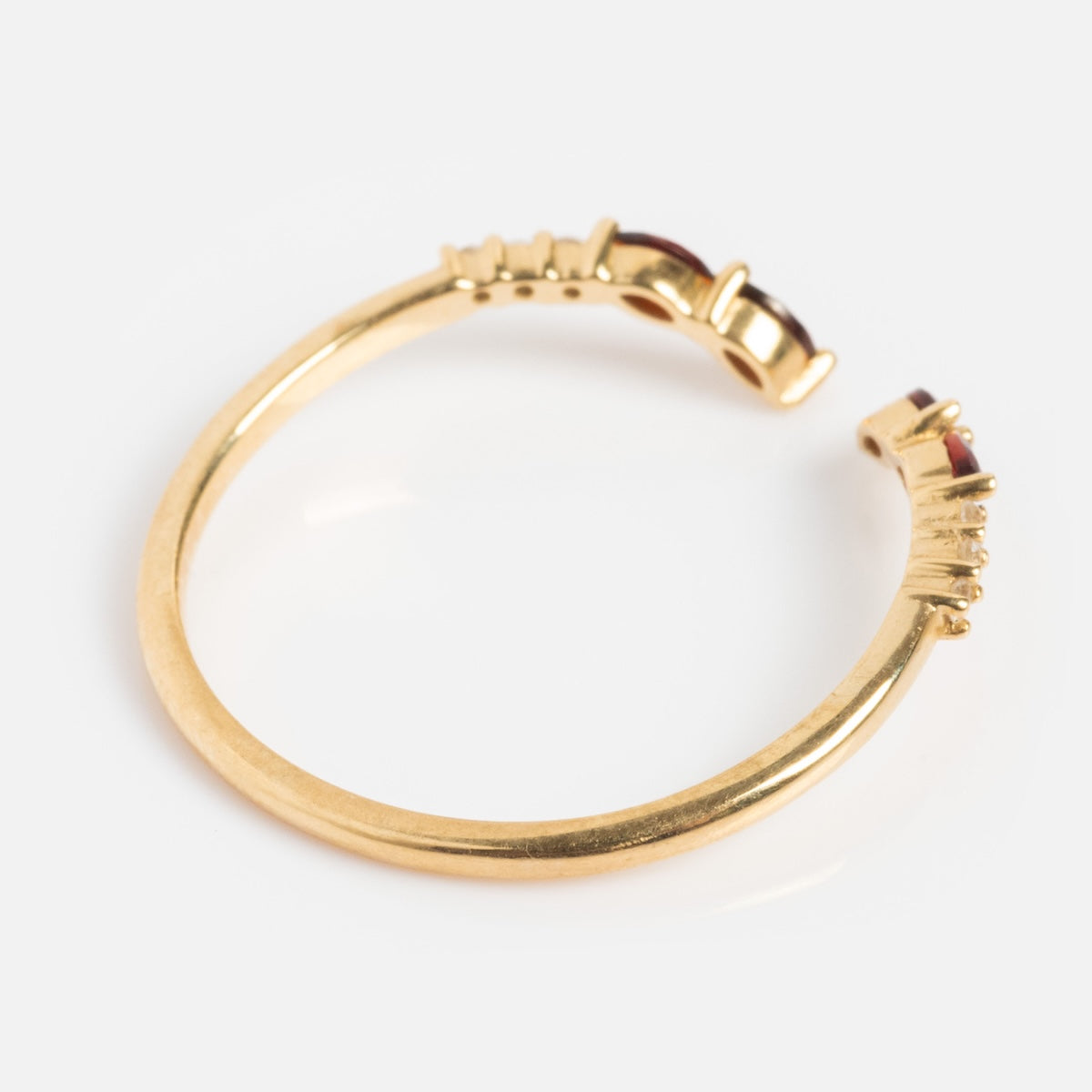The Solid Gold 2025 January Capsule Delicate Garnet Stacking Ring features small red garnet gemstones and textured ends, perfect for stacking, shown on a white background.
