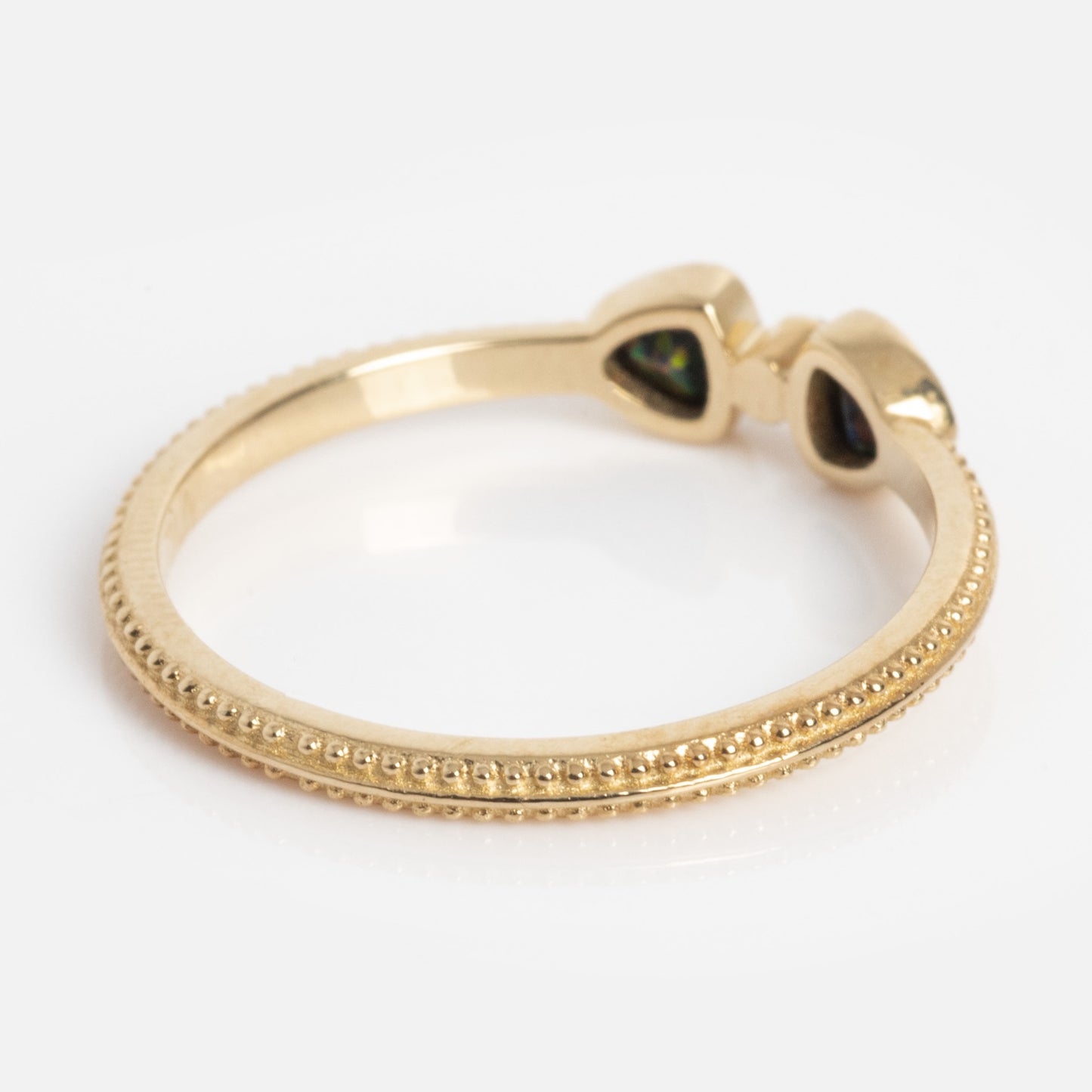 The Solid Gold Black Opal Divine Direction Ring features beaded detailing on the band and two teardrop-shaped black opals set side by side, shown against a white background.