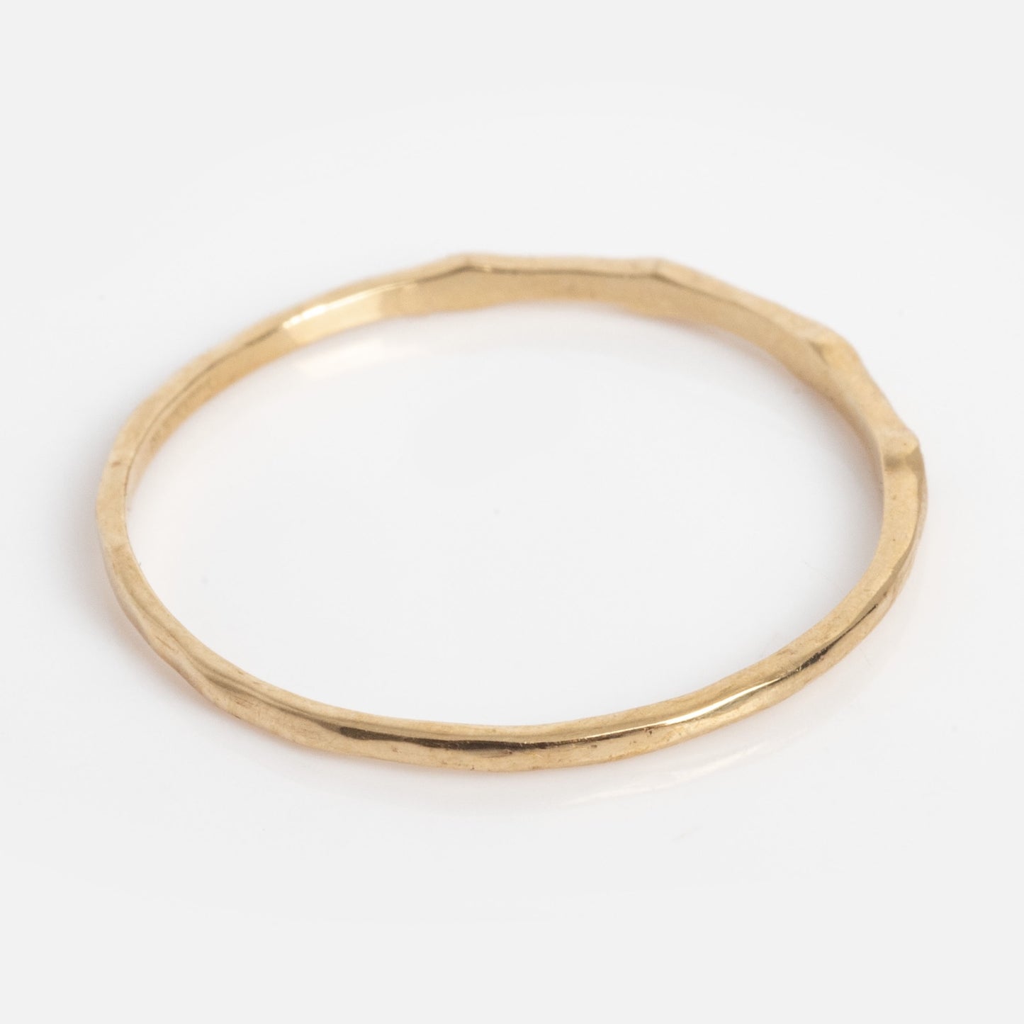 The Solid Gold Dainty Birthstone Stacking Ring features a thin, hammered texture band and is shown against a plain white background.