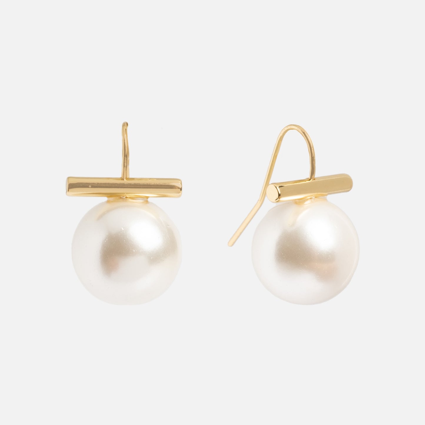 The Rory Earrings are 14k yellow gold plated hook earrings with large, round Swarovski pearls hanging below horizontal gold bars, shown on a plain white background.